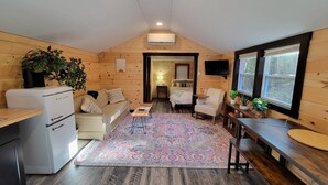 A cozy cabin interior with a kitchenette, a dining area, a living room, and a bedroom. - Travelers Haven (Whitefield)