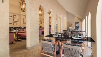 A spacious dining area with a long table, multiple chairs, and a modern chandelier.