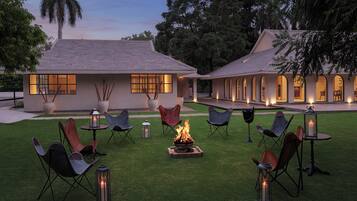 Un espacio de patio al aire libre con un brasero, asientos e iluminación ambiental.