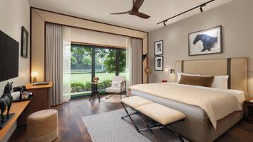 Habitación de hotel moderna con una cama grande, ventilador de techo, escritorio con lámpara, una silla y vistas al exterior.