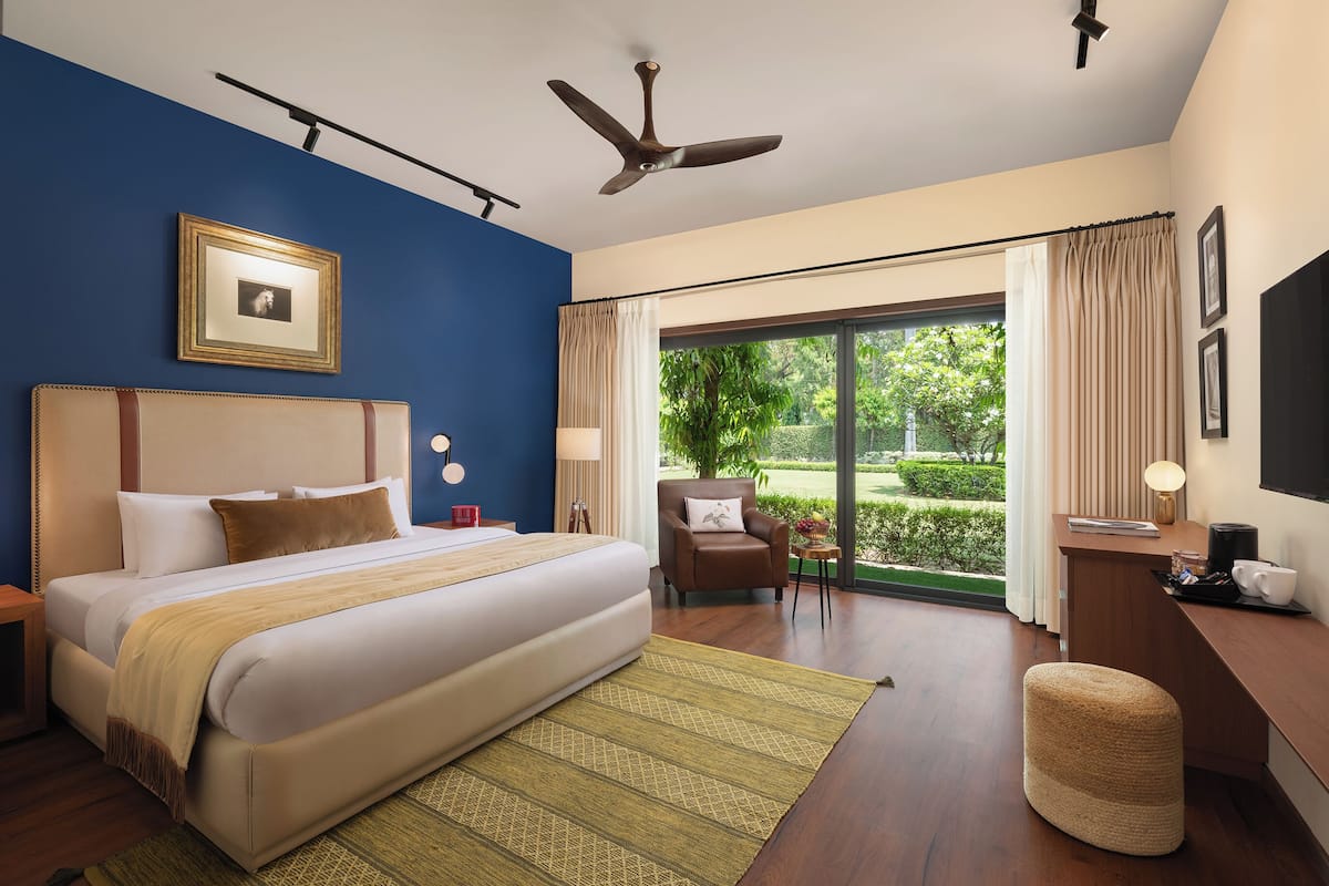 Quarto de hotel moderno com uma cama grande, uma mesa de trabalho, uma cadeira e vista para o exterior.