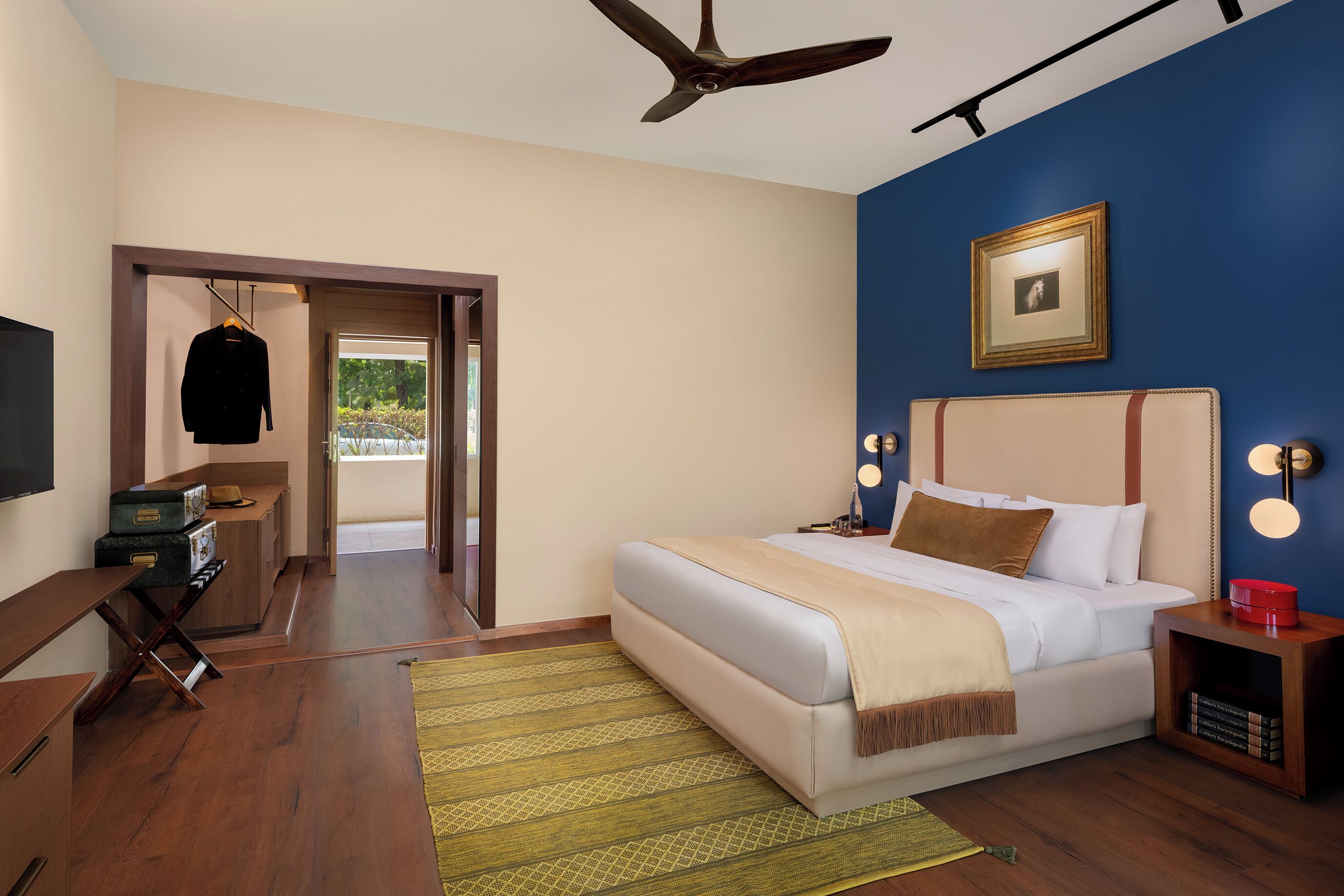 A bedroom with a bed, bedside table, lamp, and a view of the outdoors.