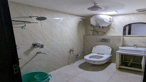 A small, compact bathroom with a toilet, sink, and shower. - Hotel The Green Arrow (New Delhi)