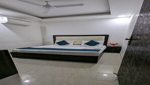 A bedroom with a bed, a ceiling fan, an air conditioner, and a tiled floor. - Hotel The Green Arrow (New Delhi)