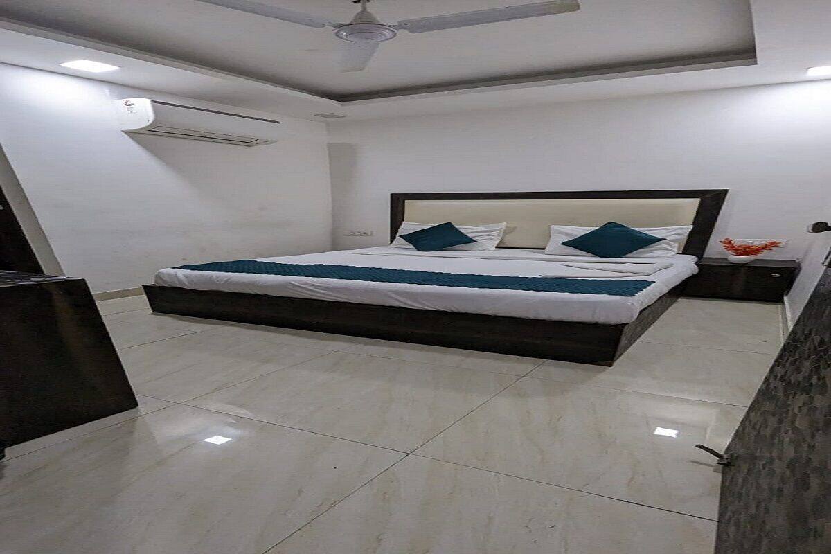 Un dormitorio moderno con una cama grande, un ventilador de techo y una mesita de noche con un florero.