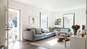 Un salon moderne avec un canapé d’angle gris, une table basse en bois et un meuble blanc.