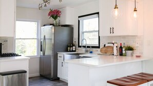Une cuisine moderne avec des meubles blancs, des appareils en acier inoxydable et un îlot central doté de sièges.