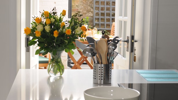 Eine Küchenarbeitsplatte mit einer weißen Schüssel, einem Blumenvasen und einem Utensilienhalter.