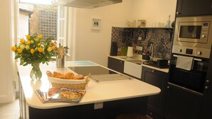 Eine moderne Küche mit einer zentralen Kochinsel, schwarzen Schränken, einer Mikrowelle und einem eingebauten Backofen.
