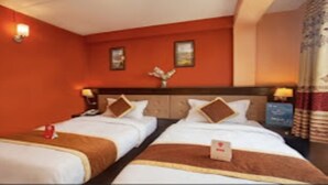 A hotel room with two beds, a wooden headboard, and a nightstand with a lamp. - MeroStay 127 Divine Guest House (Kathmandu)