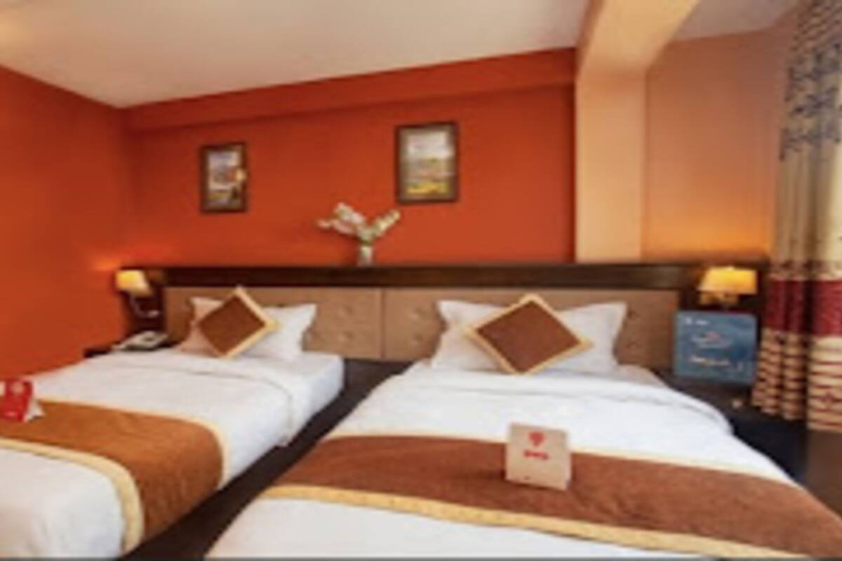 Ein Hotelzimmer mit zwei Betten, einem Holzkopfende und einem Nachttisch mit Lampe.
