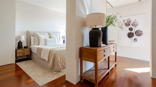 Quarto com cama, mesas de cabeceira, abajur e um quadro na parede.
