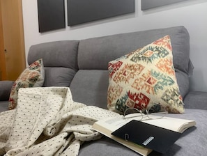 A grey sofa with patterned pillows and a polka-dotted blanket.
