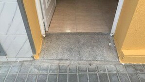 A doorway leading to a tiled interior space with a metal grate at the bottom. - Near to Beach and 15 min to Barcelona by Train (Sant Adrià de Besòs)