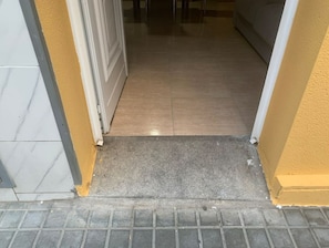 A doorway leading to a tiled interior space with a metal grate at the bottom.