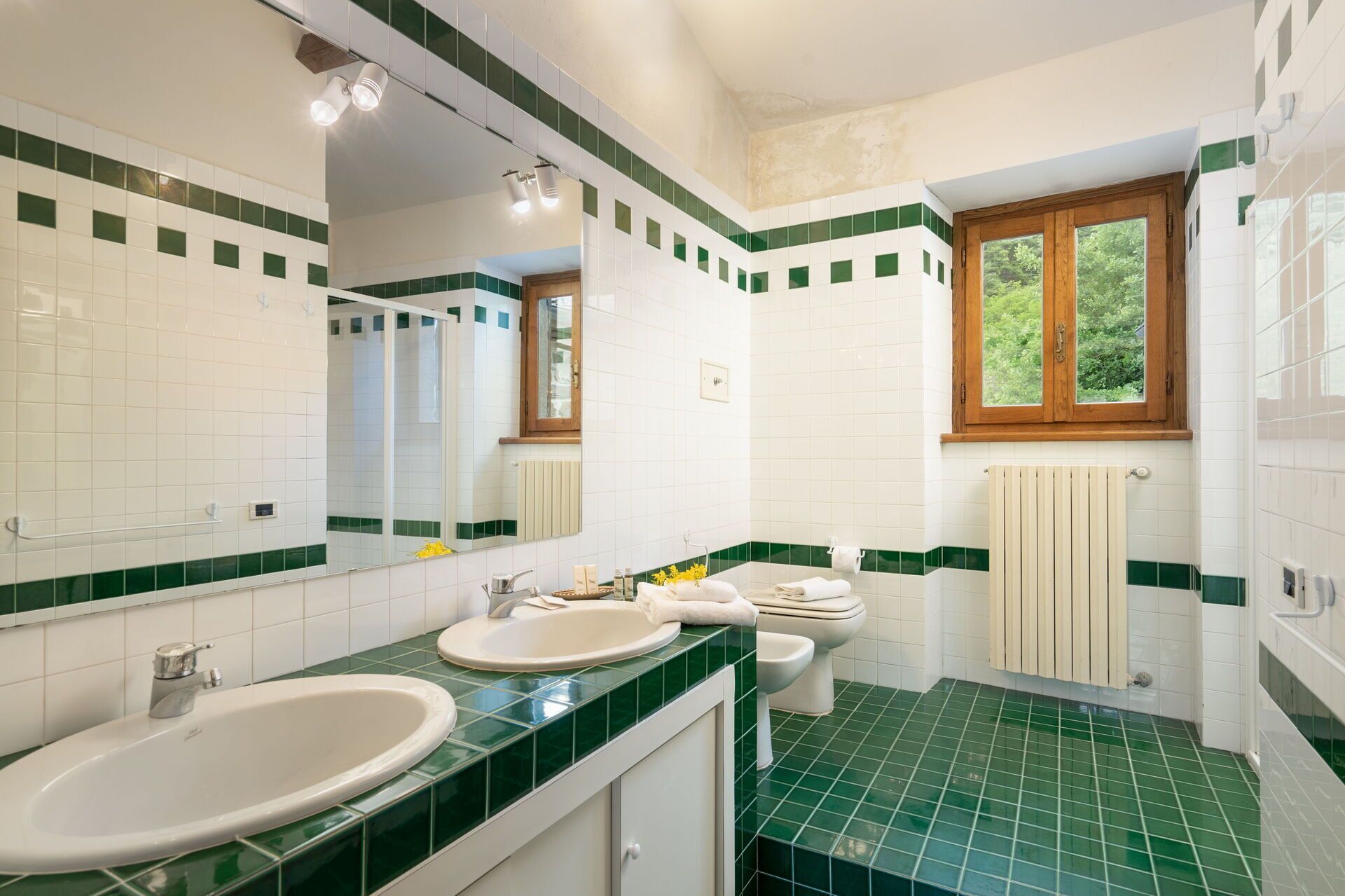 A bathroom with two sinks, a toilet, a shower, and a window.