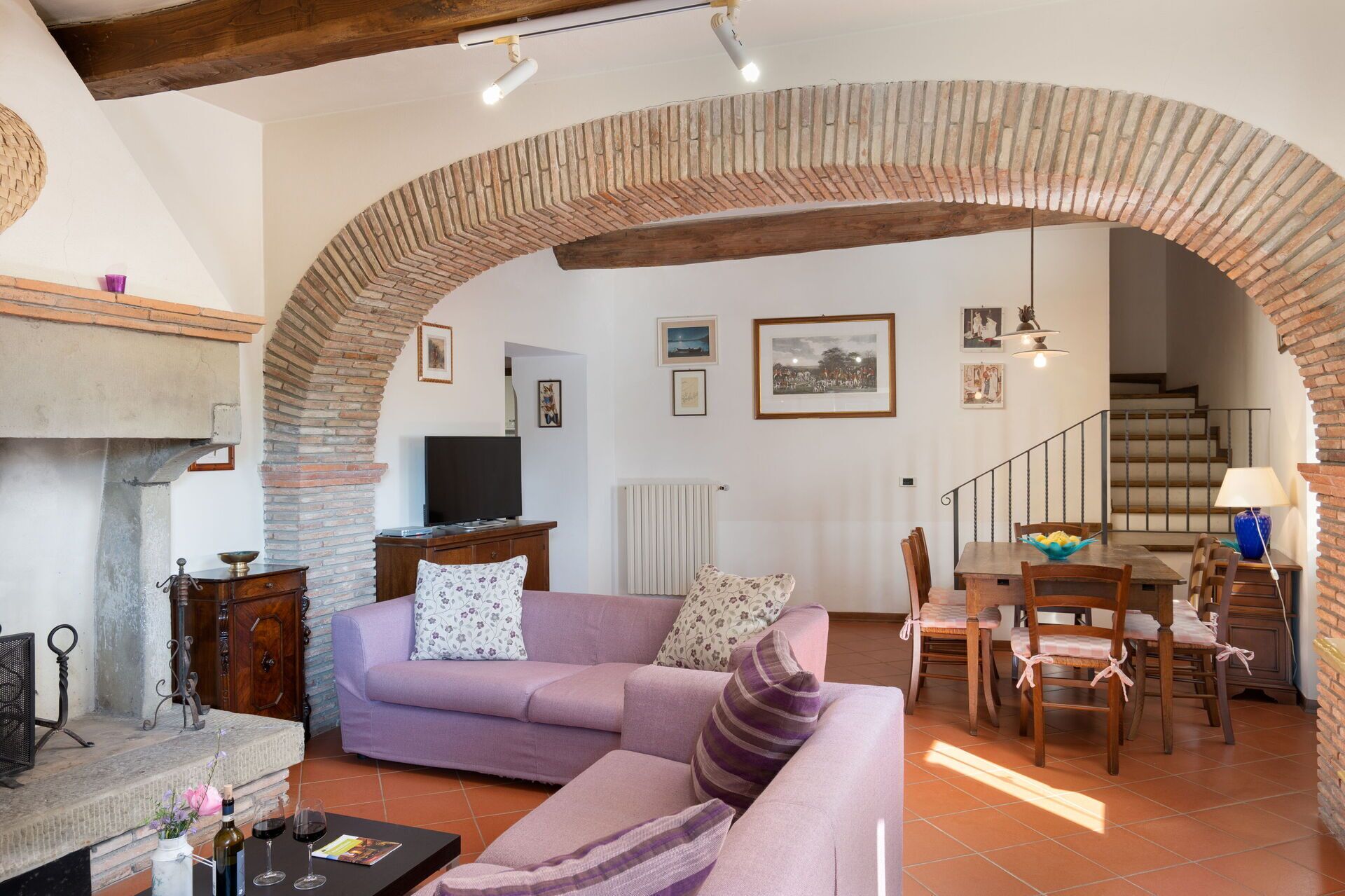 Un salon comprenant un canapé, un téléviseur, une cheminée, un coin repas et un escalier.