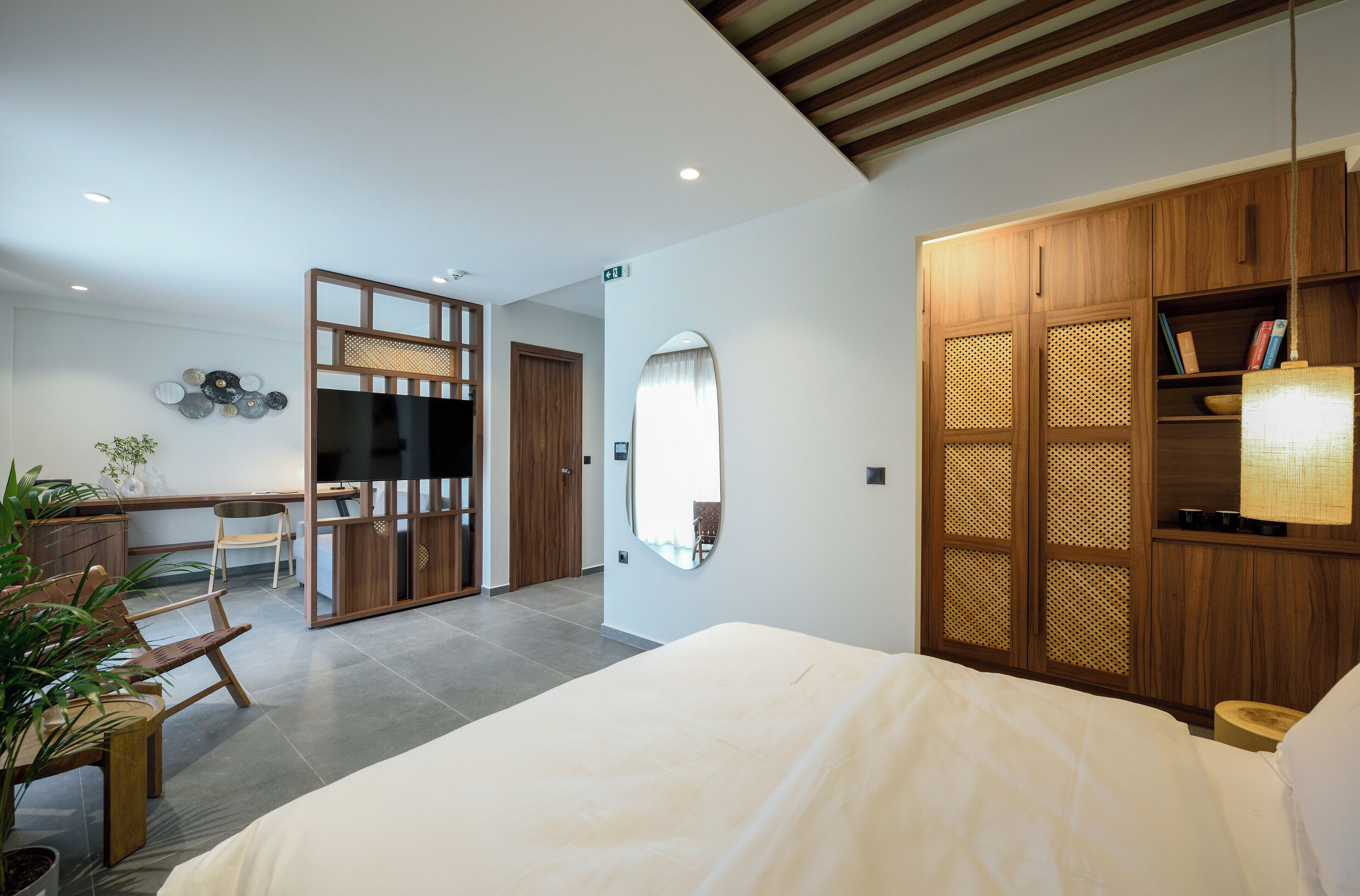 Una habitación de hotel moderna con una cama grande, un armario de madera y un escritorio con una silla.