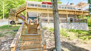 Eine zweistöckige Holzhütte mit einem Balkon, einer Treppe, die zum Eingang führt, und einem Fundament aus Stein.