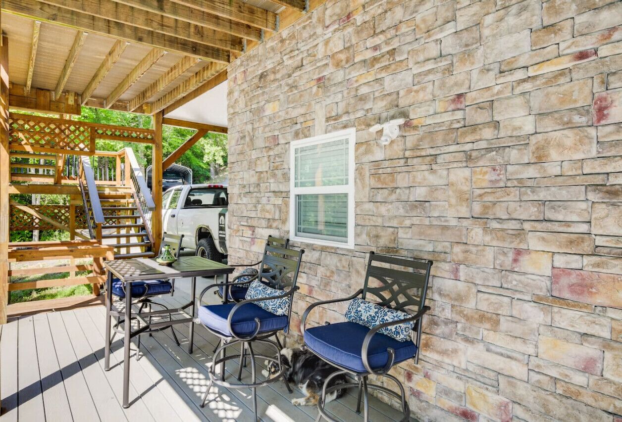An outdoor patio with stone walls, wooden furniture, and a covered seating area.