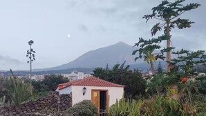 A small building with a red-tiled roof, surrounded by vegetation and a mountain in the background. - Finca Las Barandas, Vista al Mar (Icod de los Vinos)