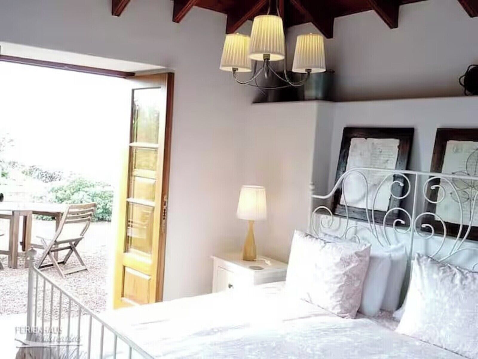 A bedroom with a bed, bedside table, lamp, and a view of the outdoors.