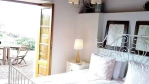 A bedroom with a bed, bedside table, lamp, and a view of the outdoors. - Finca Las Barandas, Vista al Mar (Icod de los Vinos)