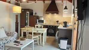 A cozy living room with a sofa, a dining table, and a kitchen area with a stove and microwave. - Finca Las Barandas, Vista al Mar (Icod de los Vinos)