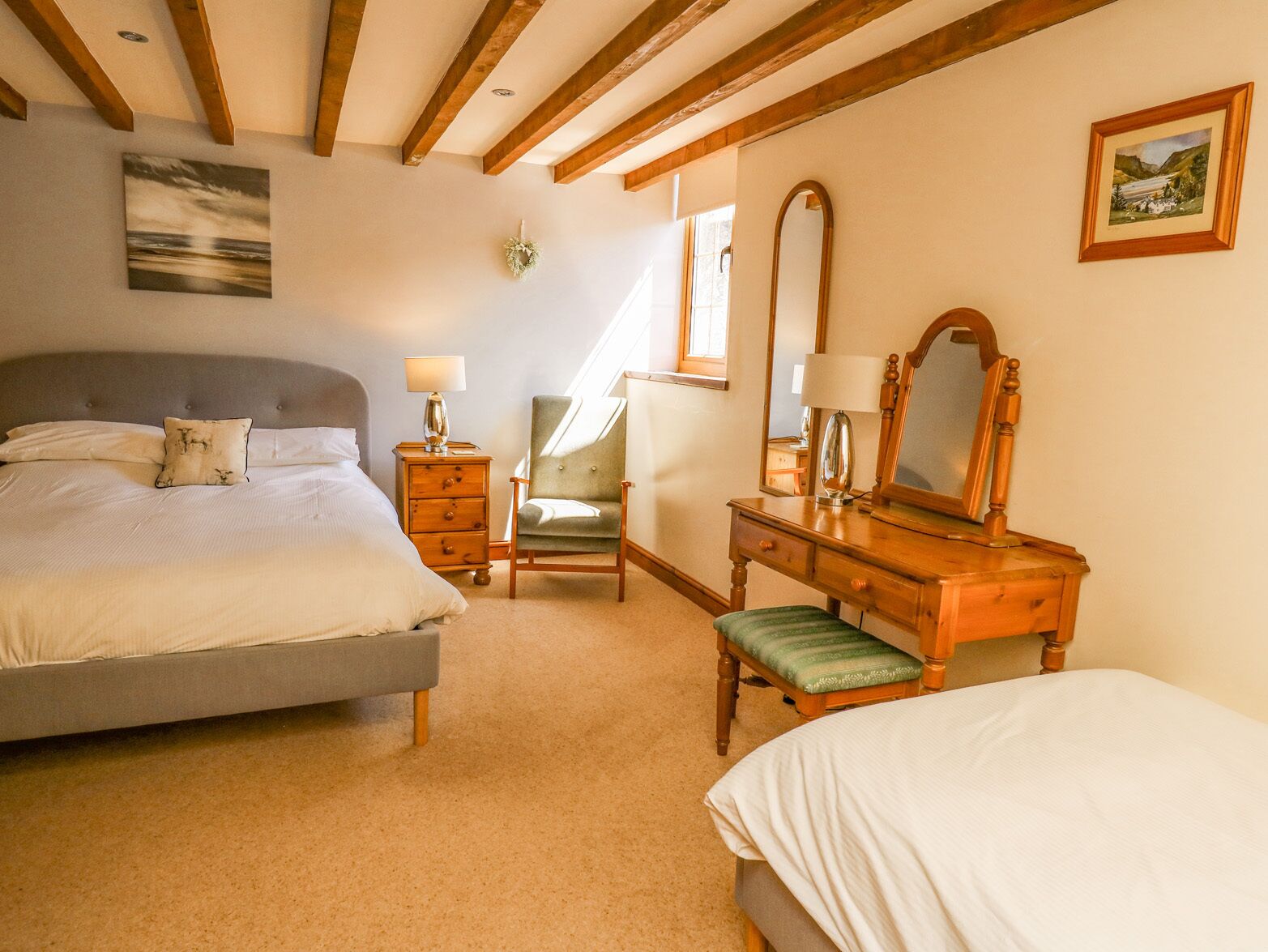 A bedroom with a bed, a dresser, a chair, and a mirror.