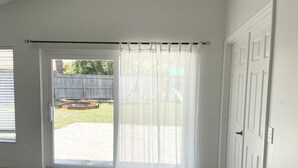 Una habitación con puerta corrediza de vidrio que da a un patio trasero.