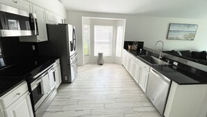 Una cocina moderna con armarios blancos, electrodomésticos de acero inoxidable y una encimera negra.