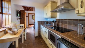A kitchen with wooden cabinets, a stove, and a dining area with a table and chairs.