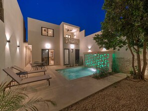 Una casa moderna amb piscina, mobiliari exterior i una paret decorativa.