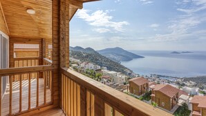 A wooden balcony with a view of a coastal town and the sea.
