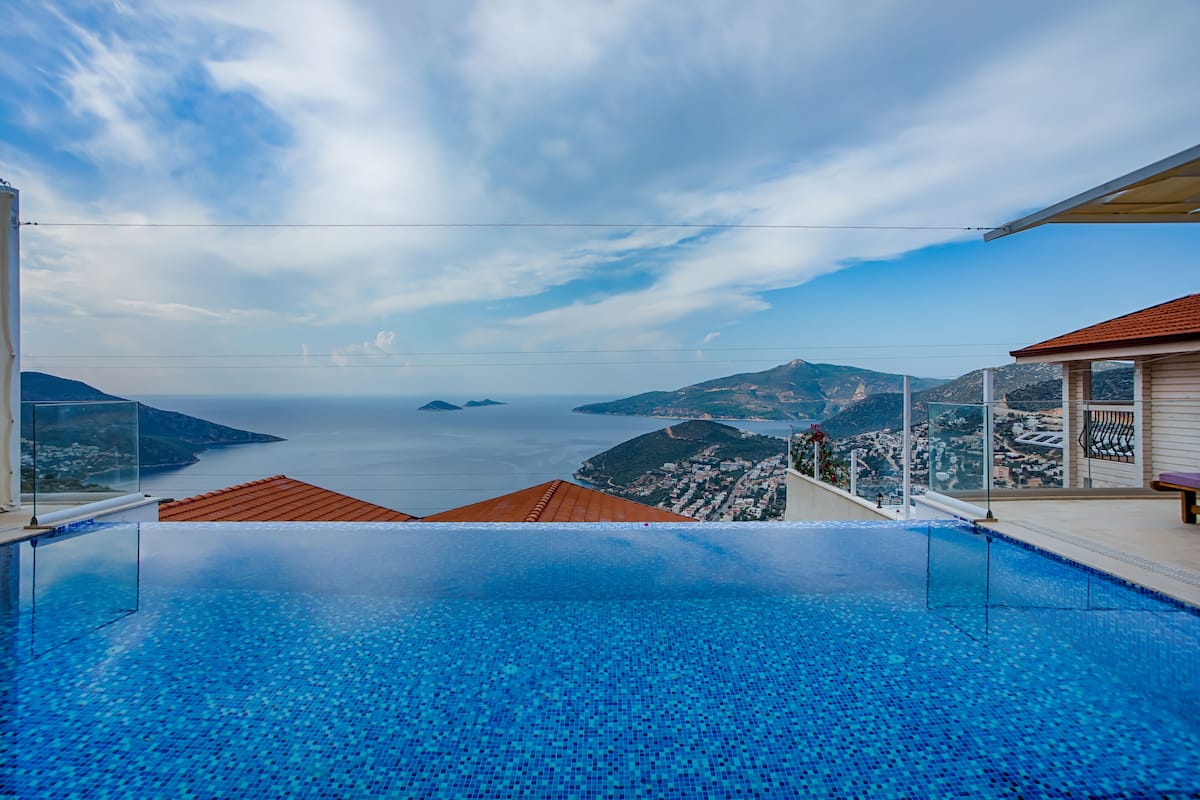 A infinity pool with a clear view of the sea and mountains.
