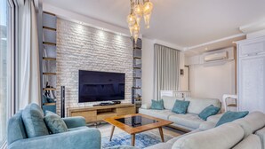 A modern living room with a flat-screen TV, a wooden coffee table, and a sofa set.