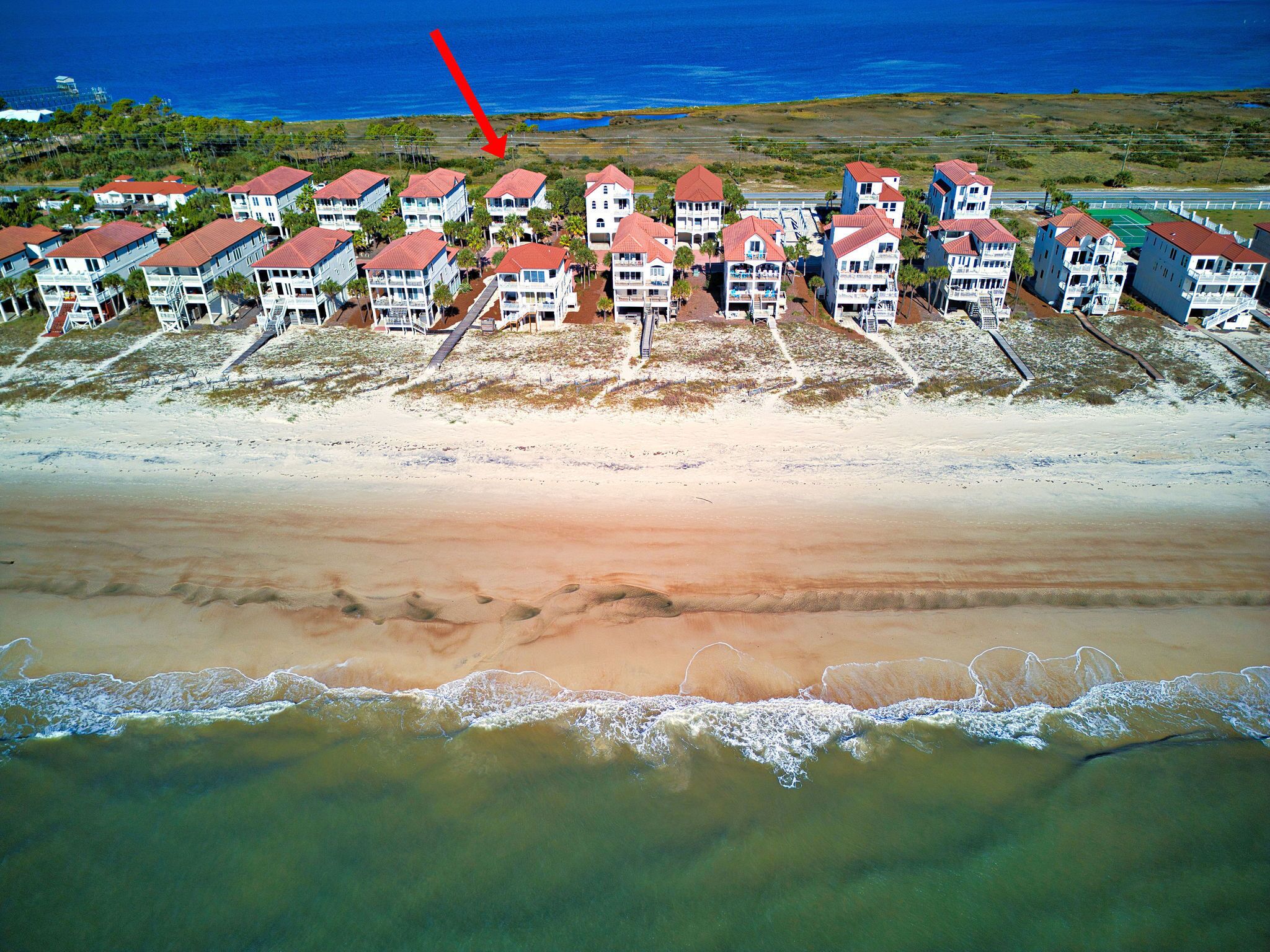 Ett hotell vid stranden med flera byggnader, en sandstrand och utsikt över havet.