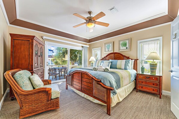 A bedroom with a wooden bed, a wicker chair, a nightstand, and a ceiling fan. - Southern Star - Across Street From Beach, Bay Views. Community Pool! (St George Island)