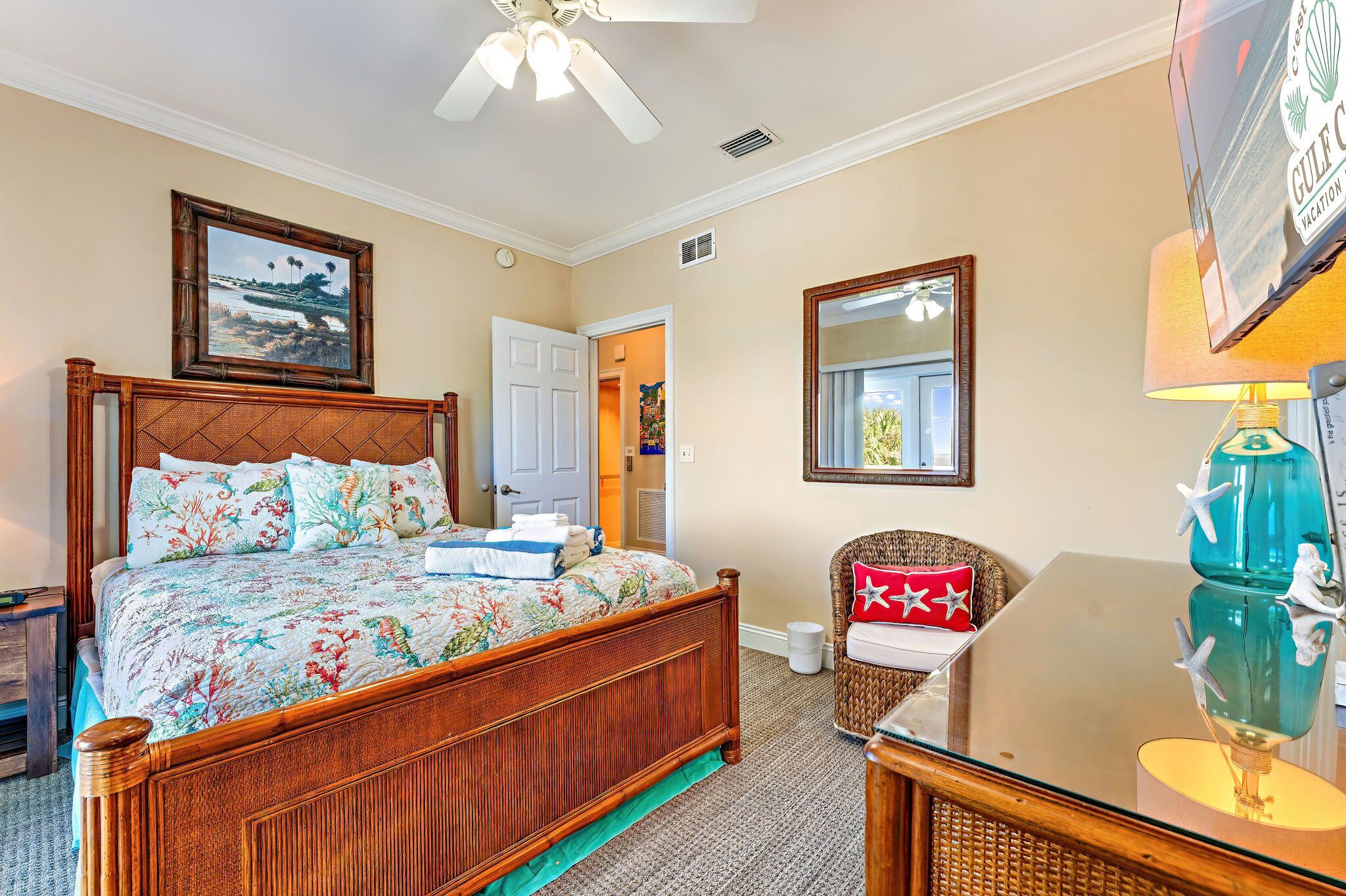 A bedroom with a wooden bed, a ceiling fan, a framed picture, a lamp, and a chair.