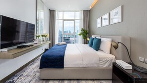 A modern hotel room with a large bed, a flat-screen TV, a city view, and a desk with a lamp. - Elegant Studio at DAMAC Privé Business Bay by Deluxe Holiday Homes (Dubai)