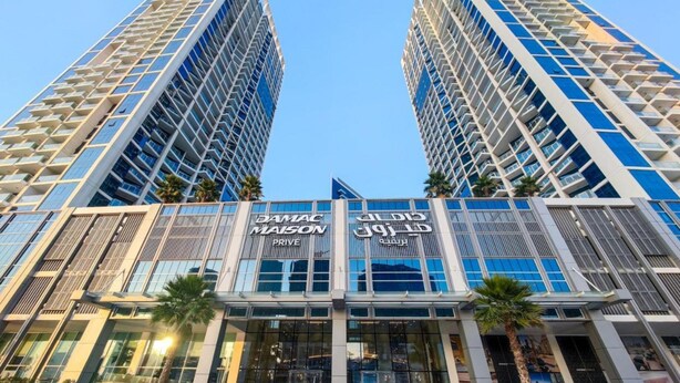Two high-rise buildings with a modern architectural design, featuring large glass windows and a prominent signage for "DANAC MASON". - Elegant Studio at DAMAC Privé Business Bay by Deluxe Holiday Homes (Dubai)