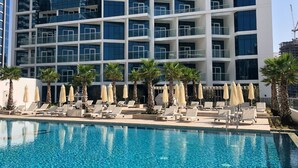 A modern hotel with a pool area, sun loungers, and umbrellas. - Elegant Studio at DAMAC Privé Business Bay by Deluxe Holiday Homes (Dubai)