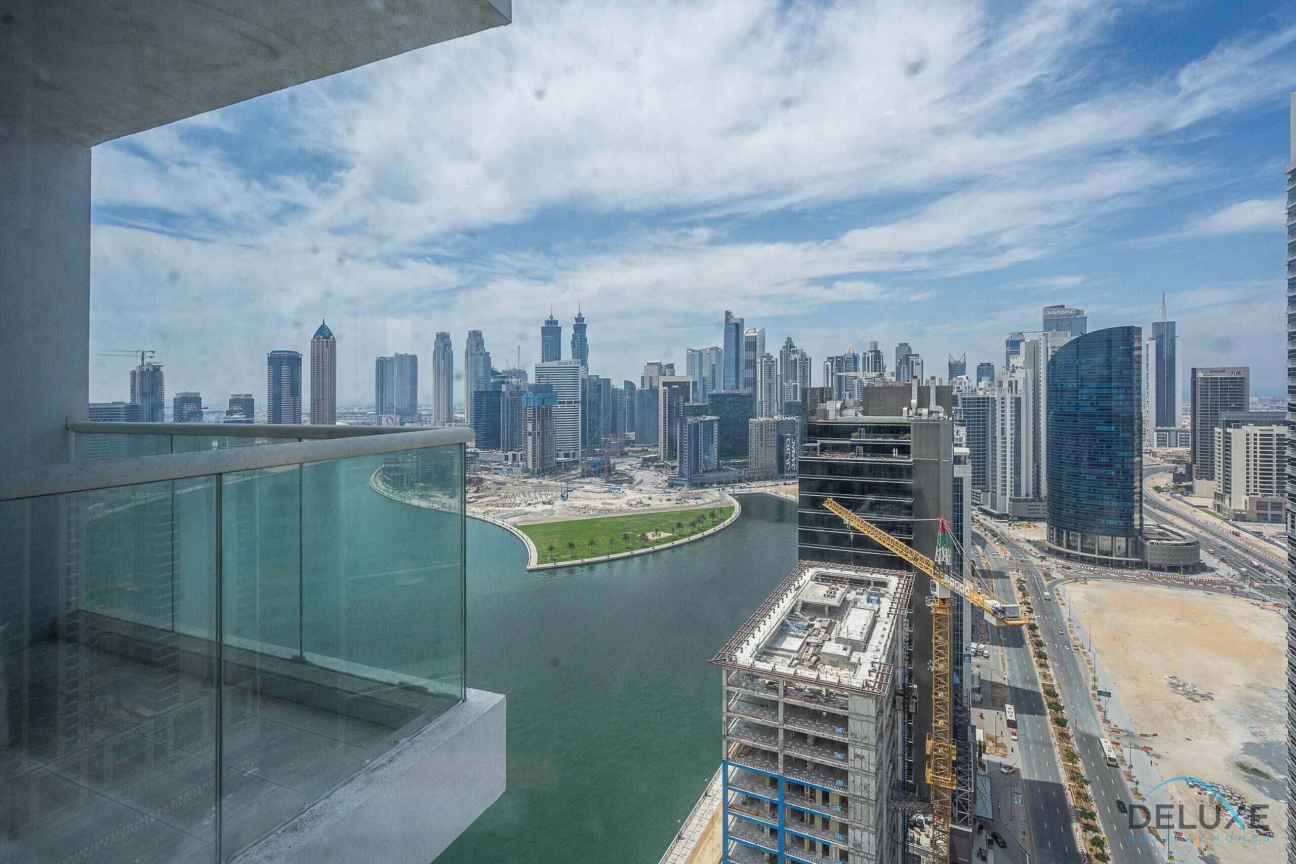A high-rise building with a view of a city skyline, a body of water, and a construction site.