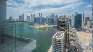 A high-rise building with a view of a city skyline, a body of water, and a construction site. - Elegant Studio at DAMAC Privé Business Bay by Deluxe Holiday Homes (Dubai)