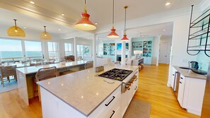 A spacious kitchen with a central island, pendant lighting, and a view of the ocean.