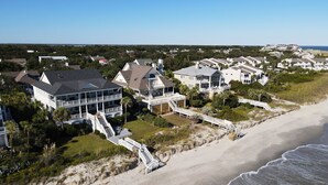 Una zona residencial costera con propiedades frente al mar, que incluyen casas de varios pisos y imponentes escaleras que dan acceso a la playa, con una vista despejada del océano.