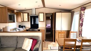 A compact RV interior with a kitchenette, a dining area, and a living space. - Cabin 38 -  Retreat Group (Aviemore)