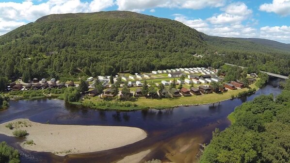 Un complexe hôtelier au bord du lac, avec des chalets et un pont enjambant la rivière.