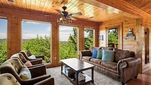 A wooden interior with a brown leather sofa, a coffee table, and a ceiling fan. - Mountain View! Cabin, 6BR, Yard, Firepit, GameRoom (Sevierville)