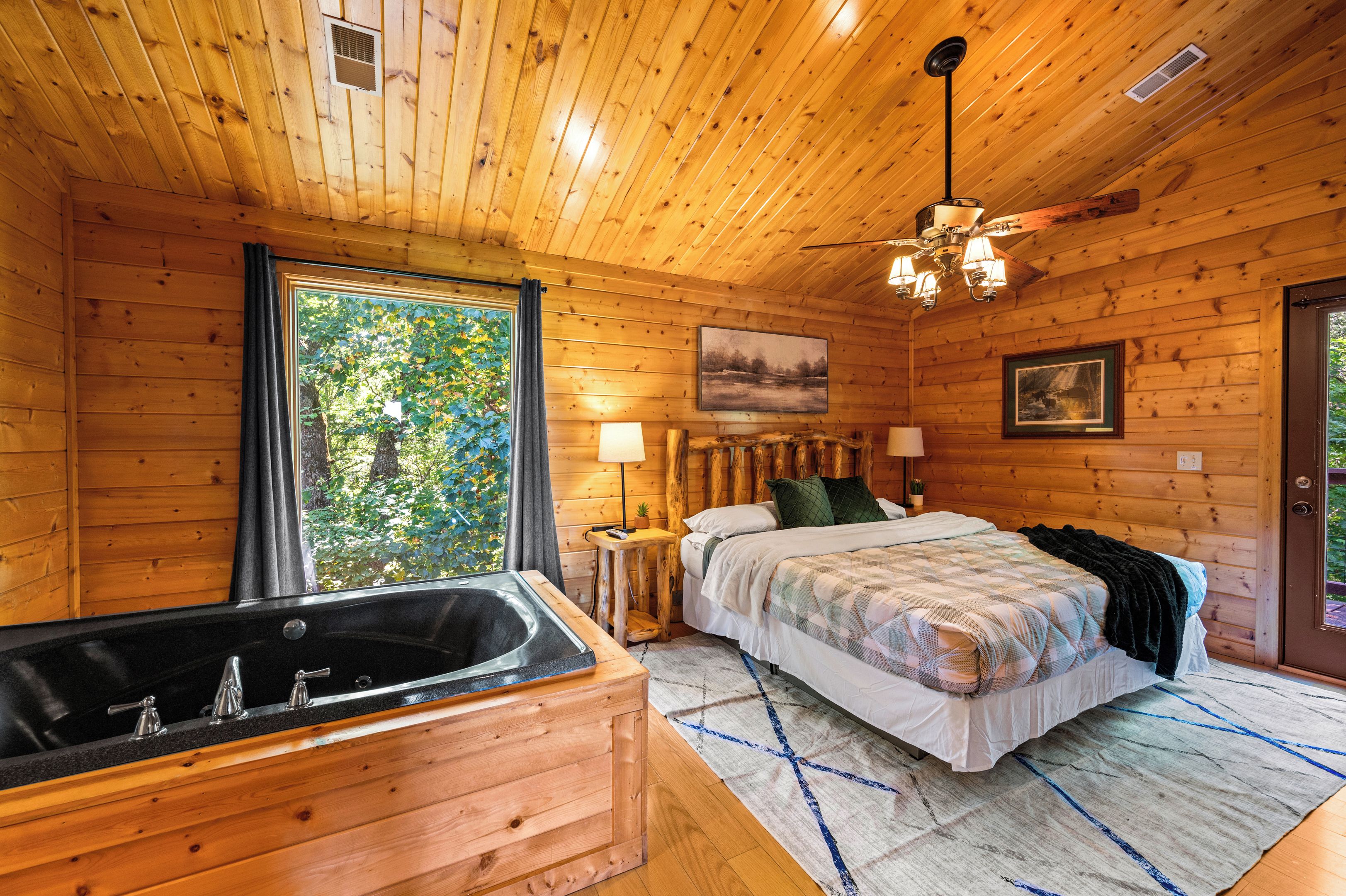 Habitación de cabaña de madera con cama, bañera de madera y ventilador de techo.